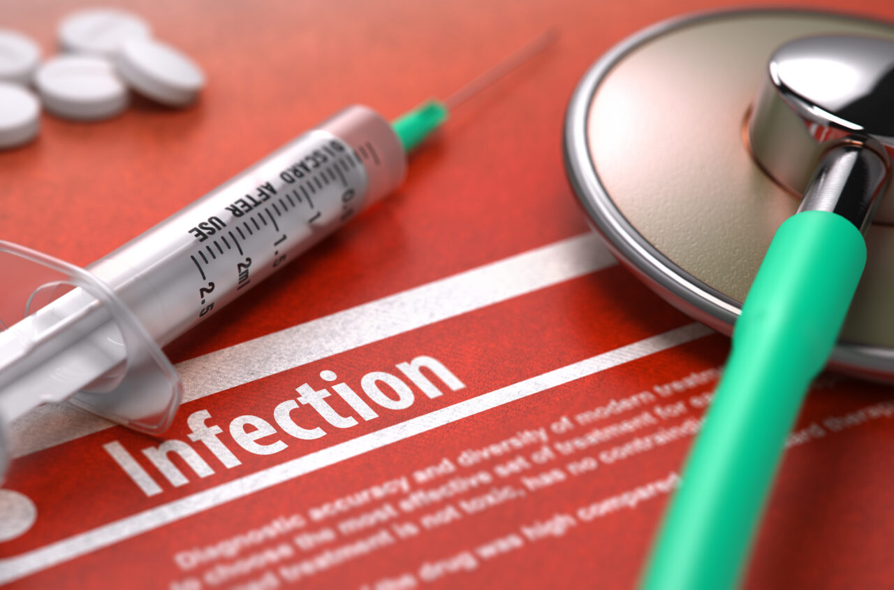 Syringe, pills, and a stethoscope on a red surface related to infection prevention and control - suggesting possible Failure to Diagnose or Treat Infections.